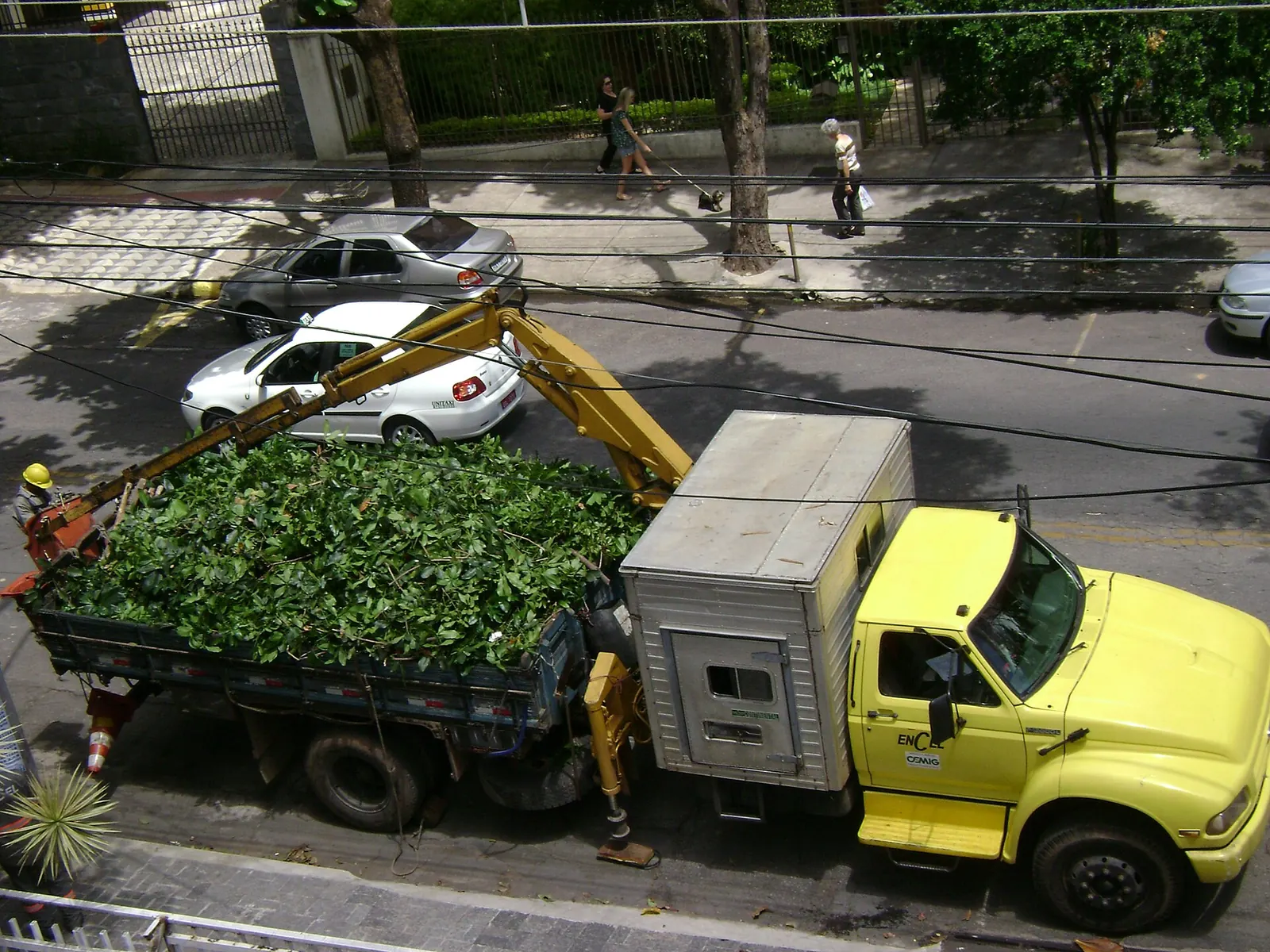 Truck-mounted knuckleboom crane loading tree debris on a city street